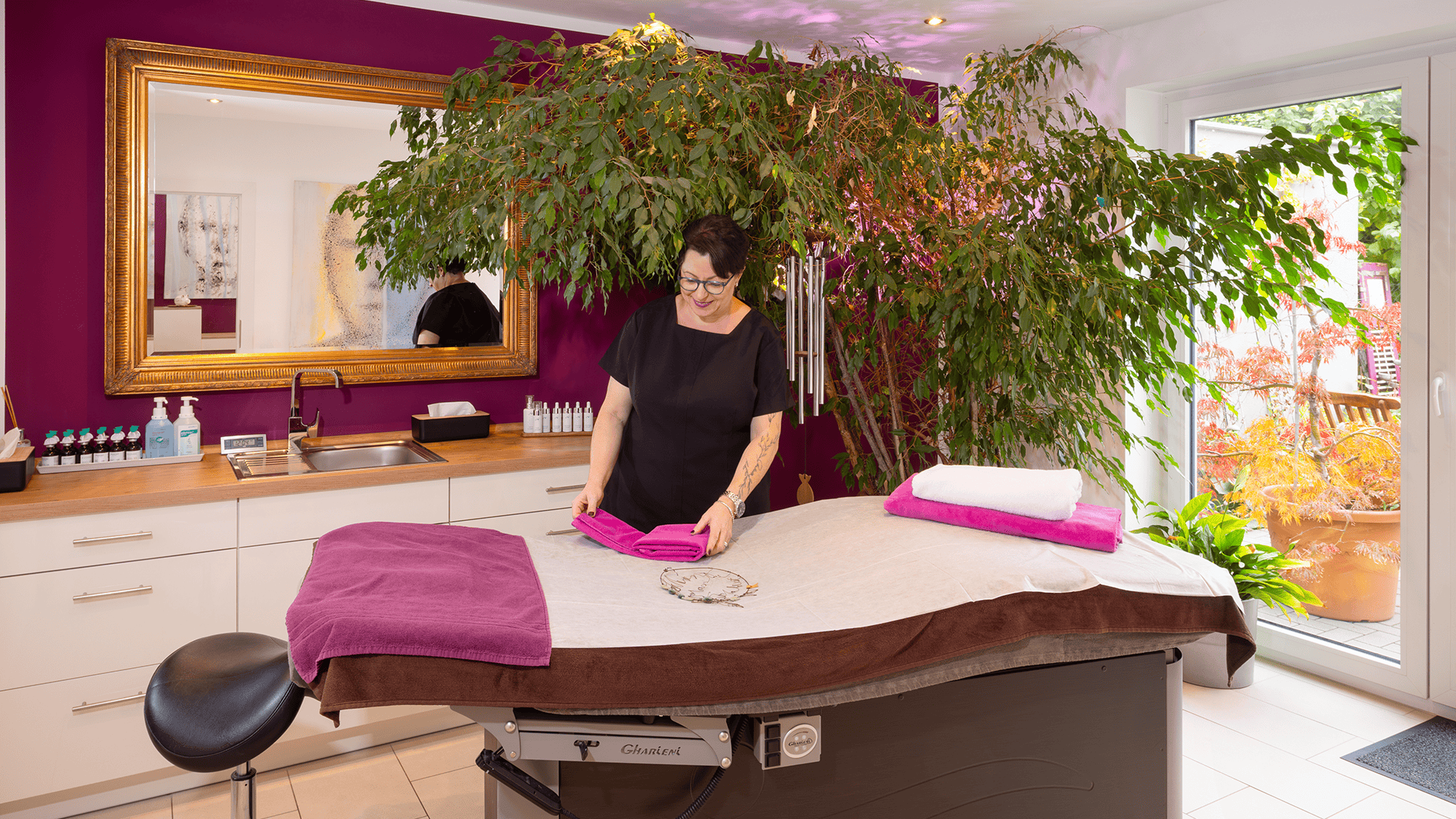 Frau bereitet Massagetisch mit pinken Handtüchern vor